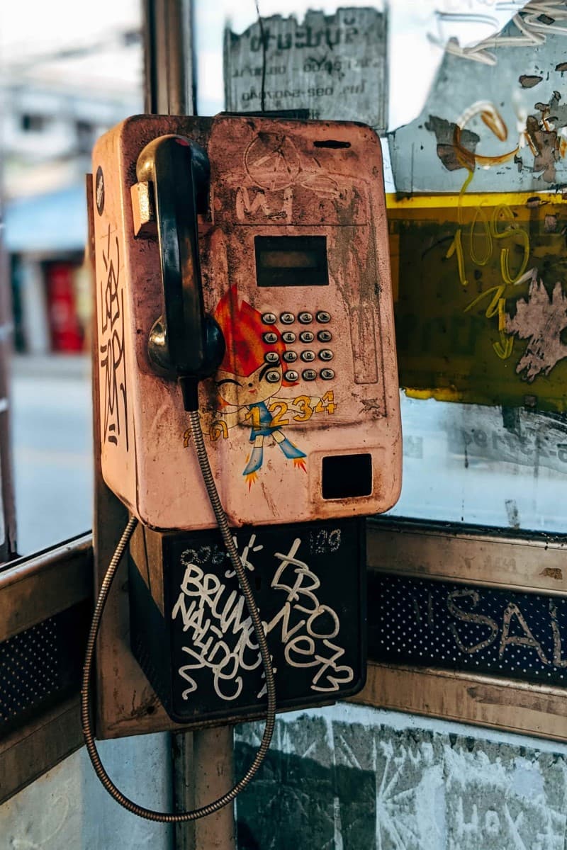 an old payphone with art painted over dirt.